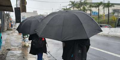 Pedestres se protegem da chuva na Avenida Interlagos, no Jardim Cons&oacute;rcio, zona sul de S&atilde;o Paulo, nesta sexta-feira, 2 de outubro de 2026 Foto: MARCO AMBROSIO/ATO PRESS/ESTAD&Atilde;O CONTE&Uacute;DO