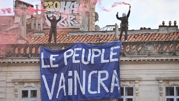 Protesters hold a banner reading "The people will win" as they stand on the roof of a building during a demonstration to protest against the "high cost of living", in Montpellier