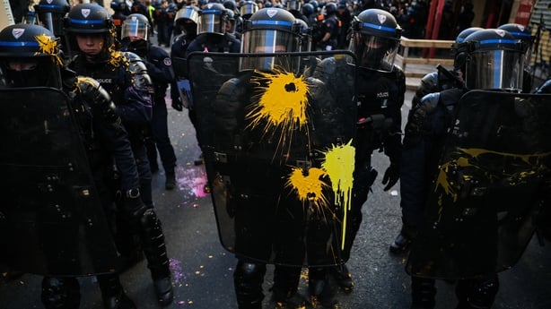 A police officer holds a protective shield covered in paint during a demonstration to protest against the "high cost of living", in Paris